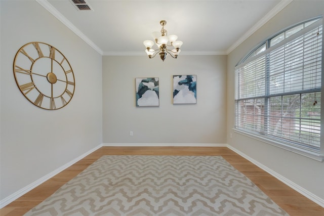 spare room with crown molding, light wood finished floors, visible vents, and an inviting chandelier