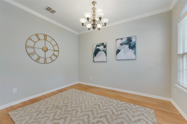 empty room featuring light wood-style floors, visible vents, a chandelier, and crown molding