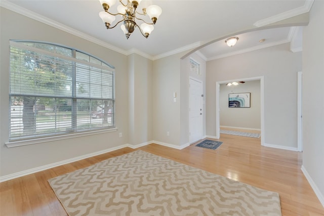 interior space with a chandelier, arched walkways, crown molding, and wood finished floors