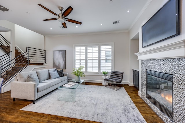 living area featuring dark wood-style floors, visible vents, crown molding, and a fireplace