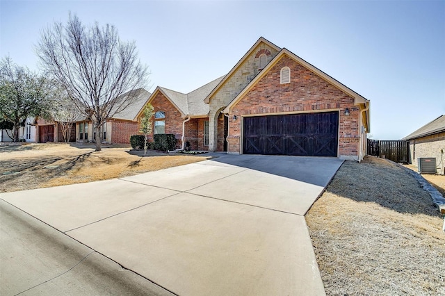 traditional home featuring driveway, a garage, fence, and brick siding