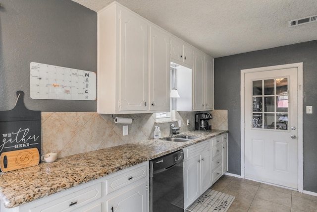 kitchen with light tile patterned floors, a sink, visible vents, white cabinets, and dishwasher