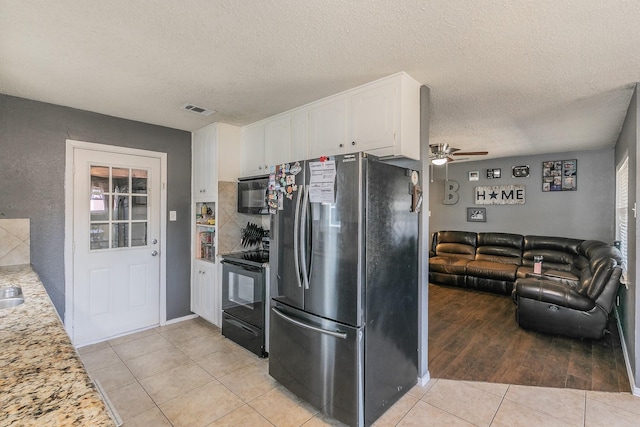 kitchen featuring visible vents, open floor plan, black appliances, white cabinetry, and light tile patterned flooring