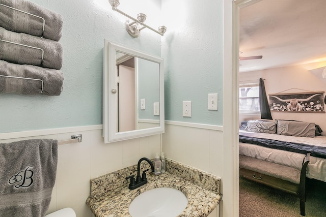 bathroom with a wainscoted wall, vanity, and ensuite bathroom