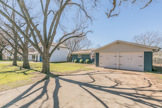 view of front of house with a garage, concrete driveway, an outdoor structure, and a front lawn