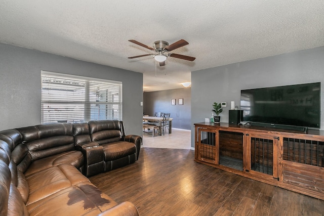 living room featuring ceiling fan, a textured ceiling, baseboards, and wood finished floors