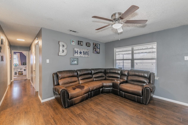 living area with baseboards, a textured ceiling, visible vents, and wood finished floors