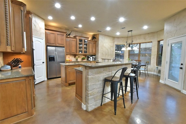 kitchen with finished concrete flooring, a large island, brown cabinetry, and stainless steel fridge