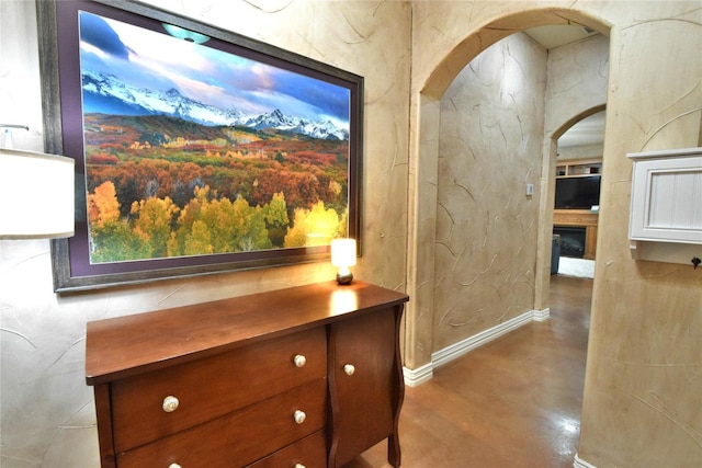 details with concrete flooring, a fireplace, arched walkways, and baseboards