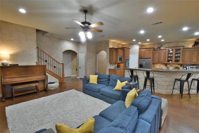 living room with arched walkways, recessed lighting, a ceiling fan, visible vents, and stairway