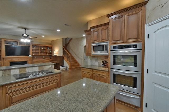 kitchen featuring brown cabinets, a warming drawer, recessed lighting, appliances with stainless steel finishes, and stone countertops