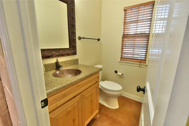 bathroom with baseboards, vanity, and toilet