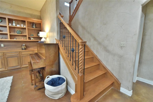 stairway featuring concrete floors and baseboards