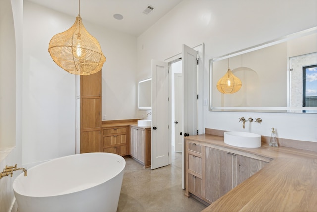 full bathroom featuring finished concrete flooring, visible vents, a sink, a freestanding tub, and two vanities