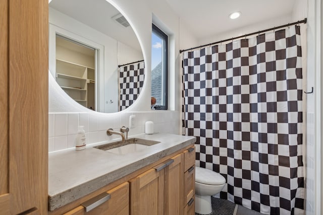 full bathroom with visible vents, decorative backsplash, toilet, vanity, and tile walls