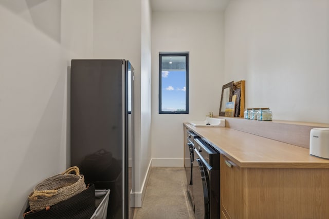 kitchen with light colored carpet, freestanding refrigerator, light countertops, and baseboards