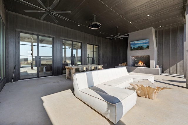 interior space with ceiling fan, a lit fireplace, recessed lighting, and wooden walls