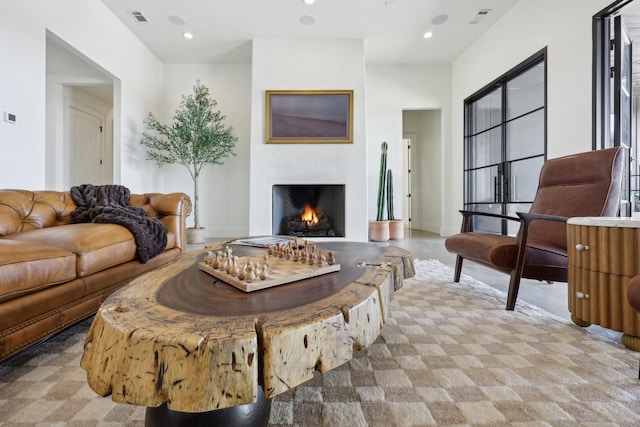 living area with a warm lit fireplace, visible vents, and recessed lighting