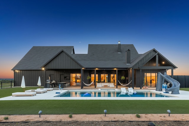 rear view of property with board and batten siding, a lawn, a patio, and fence