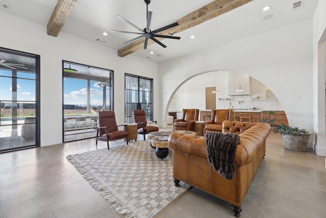 living area featuring finished concrete flooring, beamed ceiling, visible vents, and recessed lighting