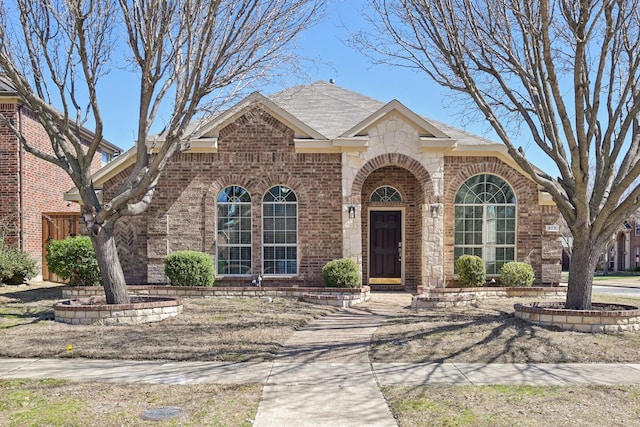 view of front facade featuring brick siding and a shingled roof