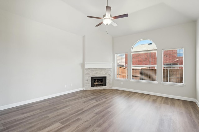 unfurnished living room with a fireplace, wood finished floors, a ceiling fan, and baseboards