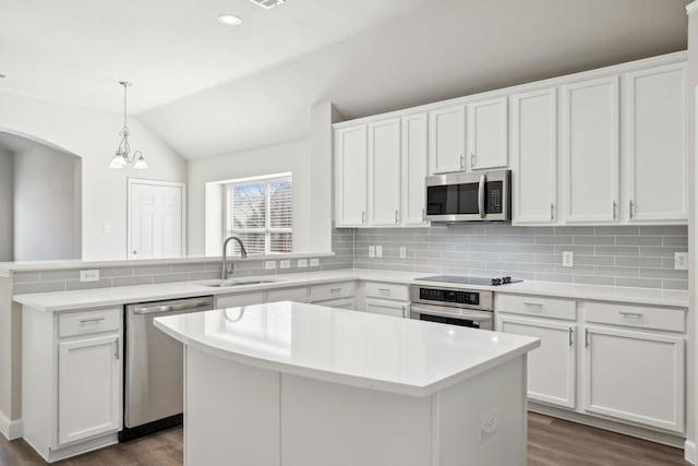 kitchen featuring tasteful backsplash, appliances with stainless steel finishes, dark wood-type flooring, a peninsula, and a sink