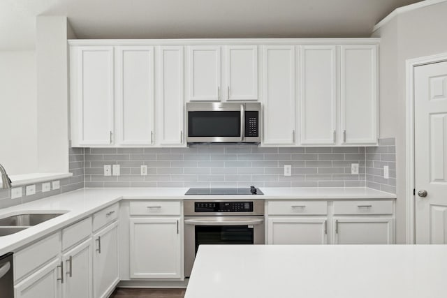 kitchen with a sink, white cabinets, light countertops, appliances with stainless steel finishes, and decorative backsplash