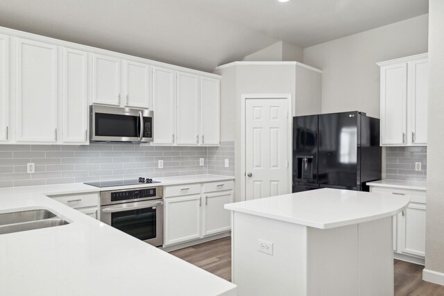 kitchen with white cabinetry, backsplash, black appliances, and wood finished floors