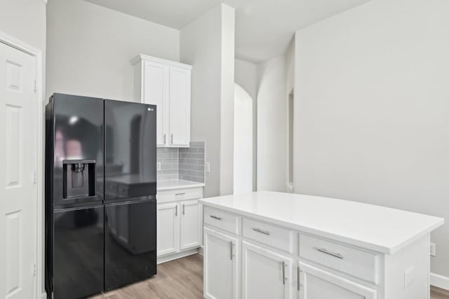 kitchen featuring light wood finished floors, tasteful backsplash, white cabinetry, and black refrigerator with ice dispenser