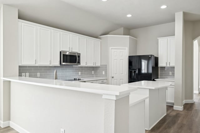 kitchen featuring a peninsula, stainless steel microwave, dark wood-style flooring, and black fridge