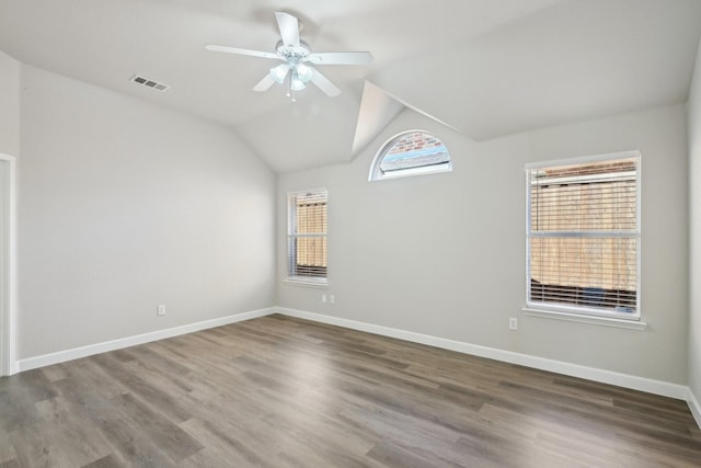 unfurnished room with a ceiling fan, visible vents, baseboards, and wood finished floors