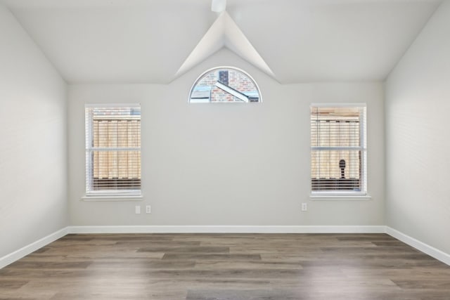 spare room featuring lofted ceiling, wood finished floors, and baseboards