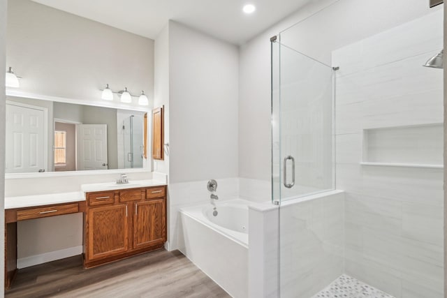 bathroom with a bath, wood finished floors, a shower stall, and vanity