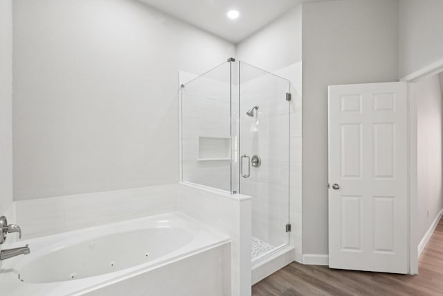 bathroom featuring a tub with jets, a stall shower, and wood finished floors