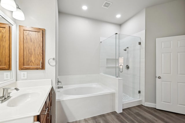 bathroom with a stall shower, visible vents, wood finished floors, a garden tub, and vanity