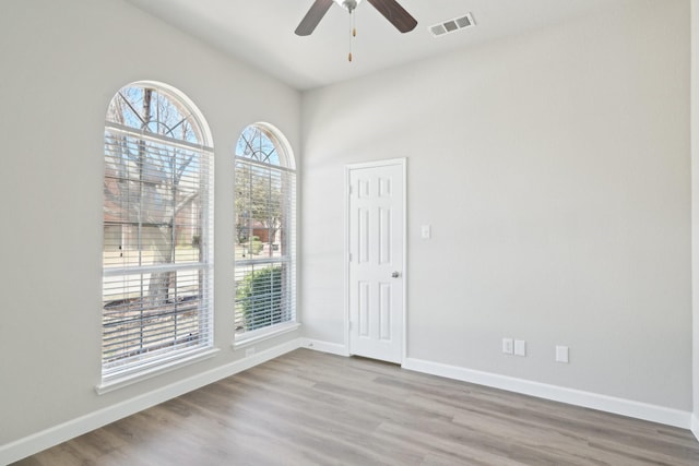 empty room featuring visible vents, ceiling fan, baseboards, and wood finished floors