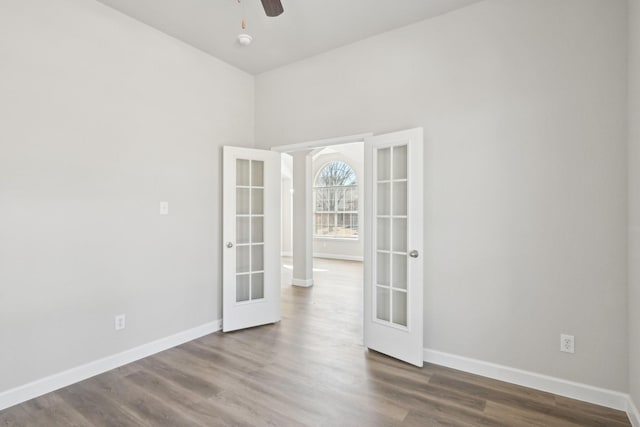 unfurnished room with ceiling fan, baseboards, wood finished floors, and french doors