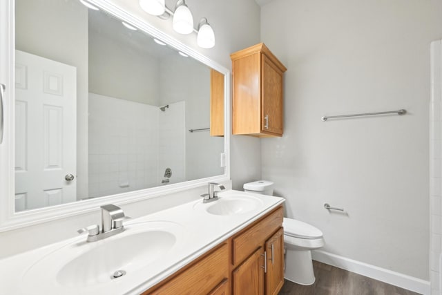 bathroom with double vanity, a sink, toilet, and walk in shower