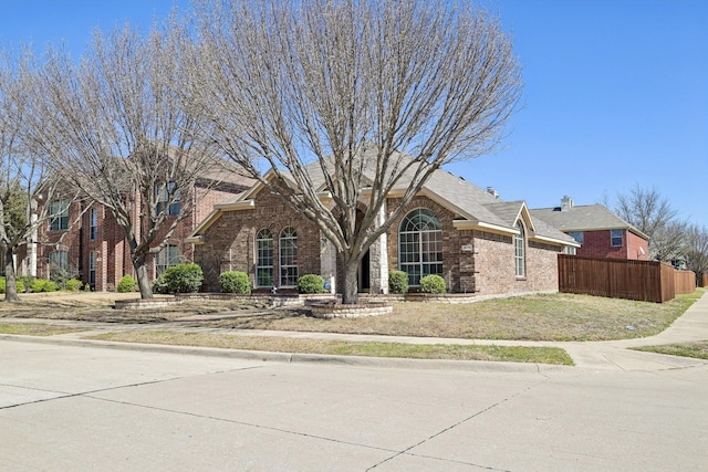 view of front of house featuring brick siding and fence