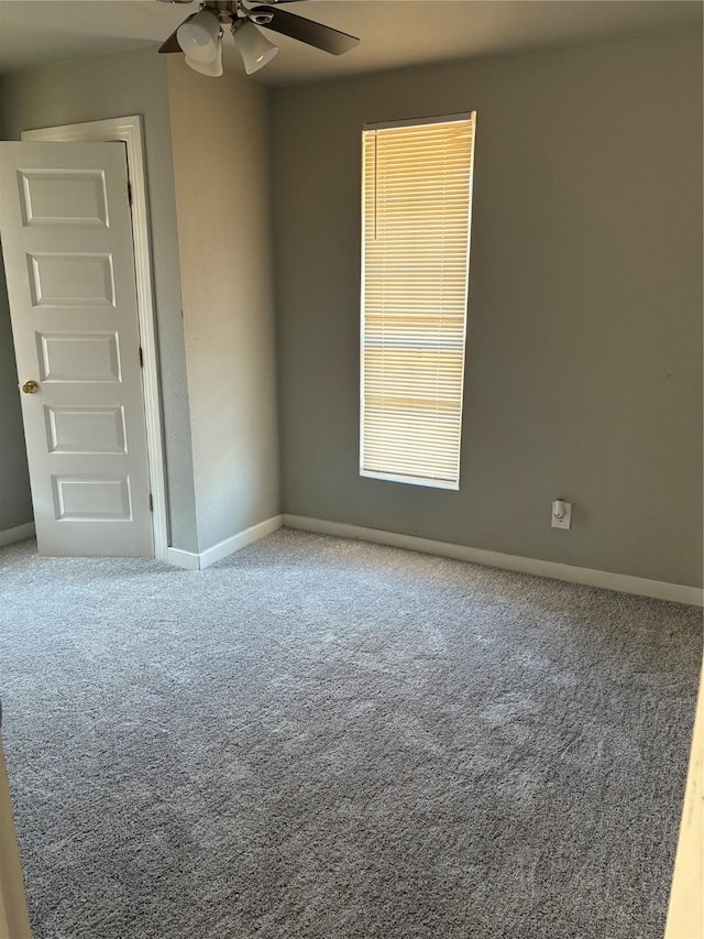 carpeted empty room featuring ceiling fan and baseboards