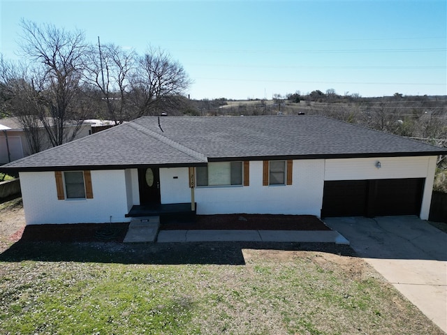 view of front facade with a garage, concrete driveway, roof with shingles, and a front yard