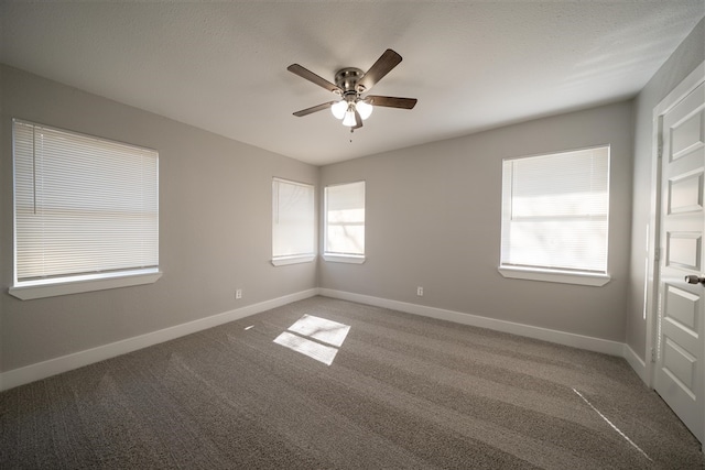 carpeted empty room featuring a ceiling fan and baseboards