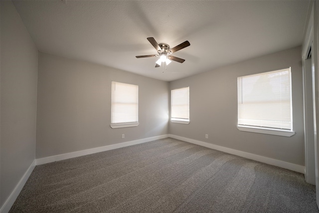 carpeted empty room featuring a ceiling fan and baseboards