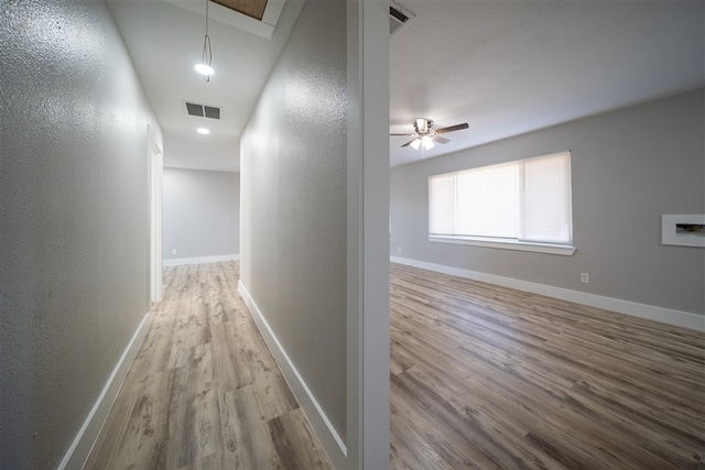 hallway featuring attic access, wood finished floors, visible vents, and baseboards