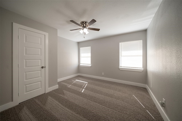 carpeted spare room with a ceiling fan and baseboards