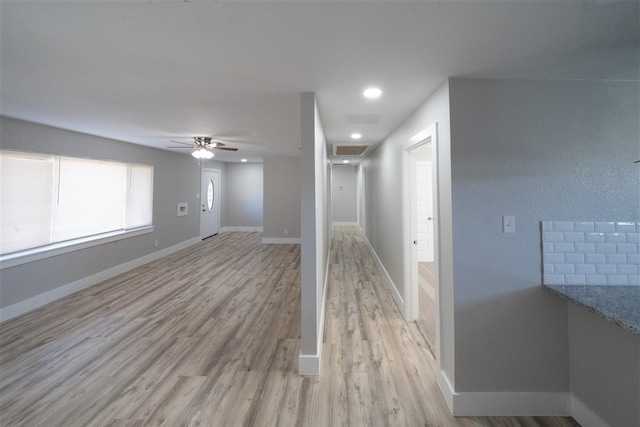 interior space with a ceiling fan, visible vents, light wood-style flooring, and baseboards