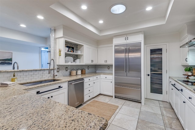 kitchen featuring a tray ceiling, appliances with stainless steel finishes, a sink, and white cabinetry