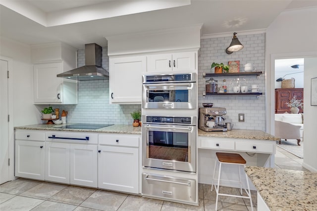 kitchen featuring a warming drawer, decorative backsplash, white cabinets, wall chimney range hood, and black electric cooktop