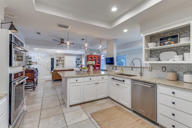 kitchen featuring stainless steel appliances, a peninsula, a sink, visible vents, and open floor plan